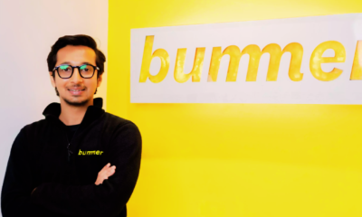 Man in glasses standing beside a yellow wall with the word "bumble" in lowercase letters.